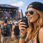 Woman using a GMRS handheld radio to communicate with friends at a crowded outdoor music festival